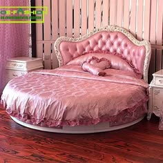 a bed with pink sheets and pillows in a room that has wooden flooring on it