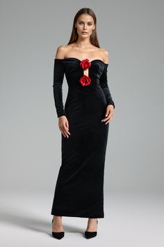 a woman in a long black dress with red flowers on the shoulder and sleeves,