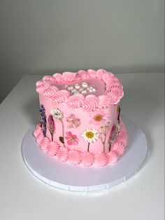 a pink cake decorated with flowers and butterflies