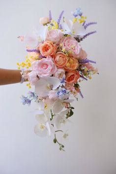 a person holding a bouquet of flowers in their hand with white and pink blooms on it