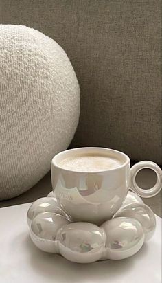 a coffee cup and saucer sitting on a table next to a white bean bag