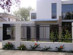 a white house with black iron fence and flowers