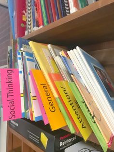 several books are stacked on top of each other in front of a book shelf full of books