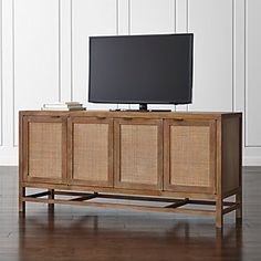 an entertainment center with wicker doors and a flat screen tv mounted on it's sideboard