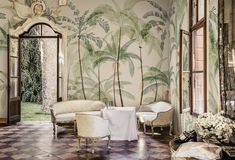 a living room with palm trees painted on the wall and chairs in front of it