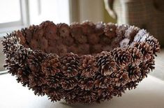 a bowl filled with pine cones sitting on top of a white table next to a chair