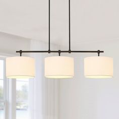 three lights hanging over a dining table in a room with white walls and flooring