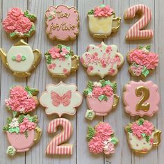 decorated cookies are arranged in the shape of numbers and teacups on a table