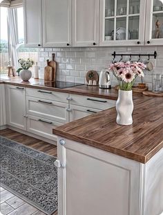 a kitchen with white cabinets and wooden counter tops