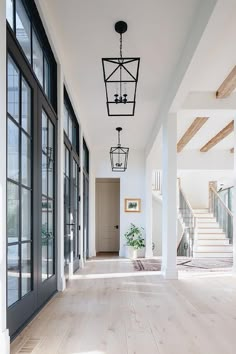 an empty hallway with wood floors and large windows