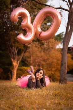 a woman laying in the grass with balloons that spell out the number thirty nine on it