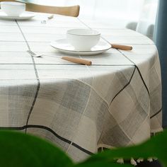 a table with a white plate and cup on top of it next to a green plant