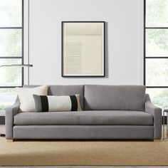 a living room scene with focus on the sofa and pillows in front of the window