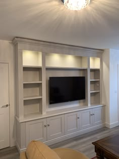 a living room with built in cabinets and a flat screen tv