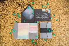 the wedding stationery is laid out on top of each other with green and silver confetti