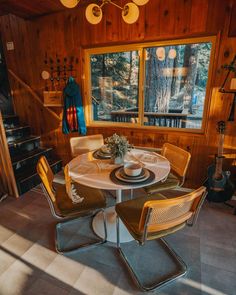 a dining room table with four chairs and a guitar on the wall next to it