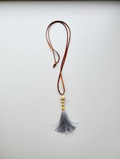 "Long Boho Chic Statement Necklace with Antique Gold Accented Grey Tassel and Wooden Beads. When I am crafting jewelry, I always have the customer in mind. I have a high standard for myself and for my customer service and can promise to give my best product at all times. Each design is truly special and unique and you can expect the same delivered to your doorstep. *ADJUSTABLE, Just tie at desired length, cut and go! Necklace Length: 34 in Plus Pendant Height: 4 in Beads: Wooden Elegant Pendant: Antique Gold Accented Grey Tassel Cording Brown Flat Leather ♥SHOW ME SOME L♡VE♥ ♥ Love it and want to buy later? Click on the heart to \"Add item to favorites.\" ♥ Love it? Share it on SOCIAL MEDIA @madebymacbeads ♥ Want it now? Click the \"Add to cart\" button. ♥ Questions about how to buy? Scrol Spiritual Tassel Necklaces With Adjustable Fit, Adjustable Spiritual Tassel Necklaces, Handmade Adjustable Brown Tassel Necklace, Brown Tassel Necklaces As Gifts, Fringe Long Necklace Gift, Long Fringe Necklaces For Gift, Fringe Long Necklace For Gift, Long Beaded Necklace With Tassels As Gift, Bohemian Tassel Necklace With Wooden Beads For Gift