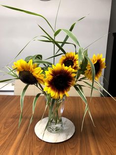 a vase filled with yellow sunflowers on top of a wooden table