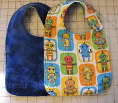 two bibs with robots on them sitting next to each other