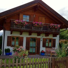 a white house with wooden shutters and flowers