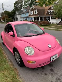 a pink car is parked on the side of the road in front of some houses