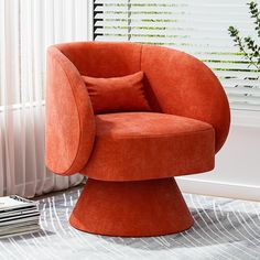 an orange chair sitting on top of a rug next to a window with white blinds