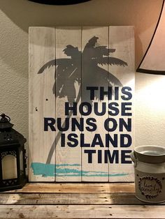 a wooden sign that says this house runs on island time next to a lamp and lantern