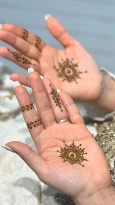 two hands with henna tattoos on them