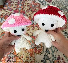 two small crocheted stuffed animals are being held by someone's hands in front of a rug