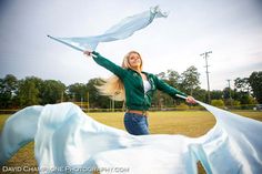 a woman is posing with her arms in the air while holding a white scarf over her head