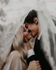 a bride and groom kissing under an umbrella