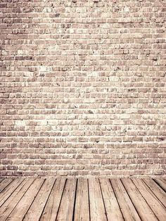 an empty wooden floor in front of a brick wall