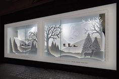 three paper cut artwork displayed in front of a window with trees and animals on it