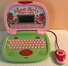 a green and pink laptop computer sitting on top of a white counter next to a red mouse