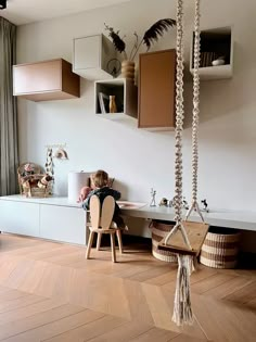 a child sitting on a chair in a room with wooden flooring and white walls