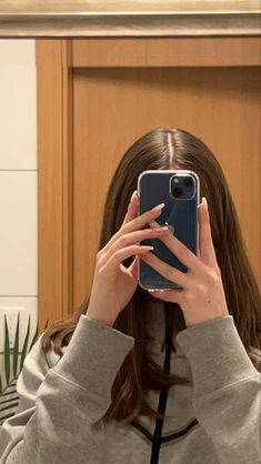 a woman taking a selfie in front of a mirror with her cell phone up to her face