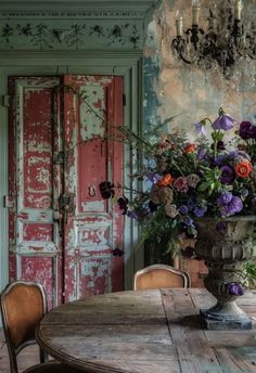 a vase with flowers on top of a table in front of an old wooden door