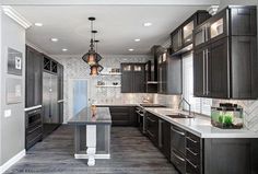 a large kitchen with black cabinets and marble counter tops