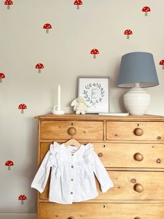 a dresser with a mushroom wall decal on it and a lamp next to it