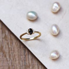 three pearls and a gold ring sitting on top of a piece of paper next to each other