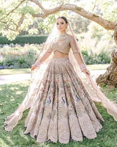 a woman in a bridal gown standing under a tree with her hands on her hips