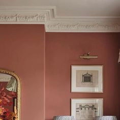 a bedroom with pink walls and pictures on the wall, along with a bed in front of a mirror