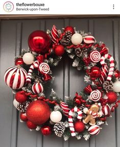 a christmas wreath with candy canes and ornaments hanging on the front door, decorated with red and white balls