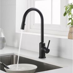 a black faucet on a white counter top next to a sink and window