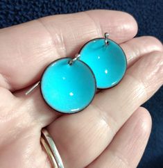 a person is holding two blue earrings in their hand and they are both wearing gold rings