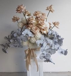 a vase filled with lots of flowers sitting on top of a white table next to a wall