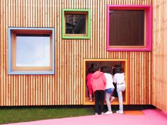 two people standing in front of a building with windows and pink carpeted flooring