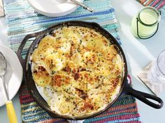 a skillet filled with food on top of a table next to plates and utensils