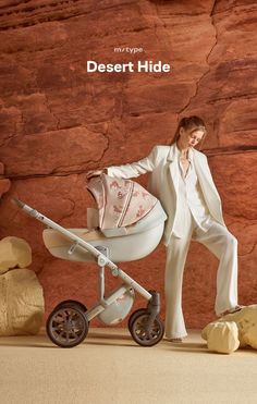 a woman standing next to a baby carriage in front of a rock wall with desert hide written on it