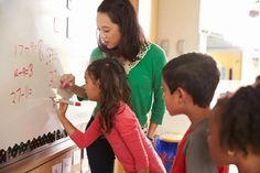 a woman teaching children how to write on a whiteboard